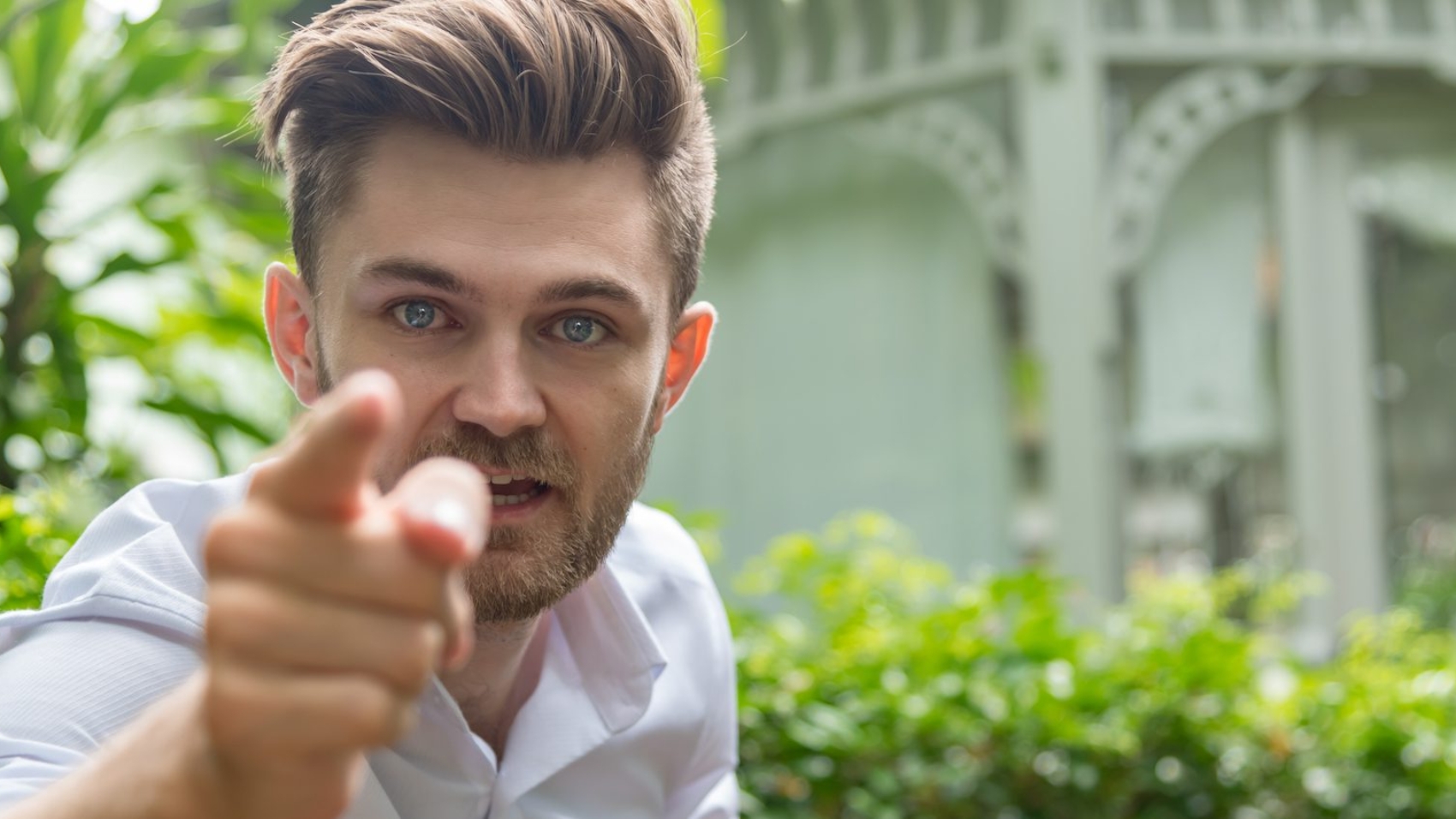 Young furious caucasian businessman shouting and pointing camera . Angry man and cursing .Anger, emotions, aggression,  Negative human emotions concept