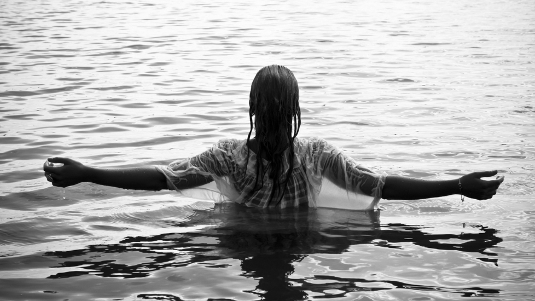 Young woman with raised arms in the water. Black and white.